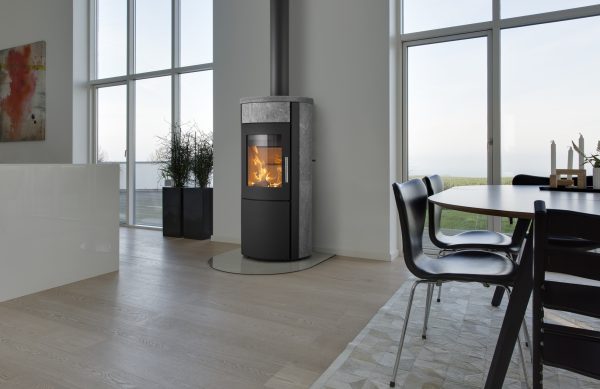 Vattenmantlad kamin HETA Scan-Line 805 Aqua i modern matsal med stora fönster. Dansk design, effektiv värme och elegant täljsten.