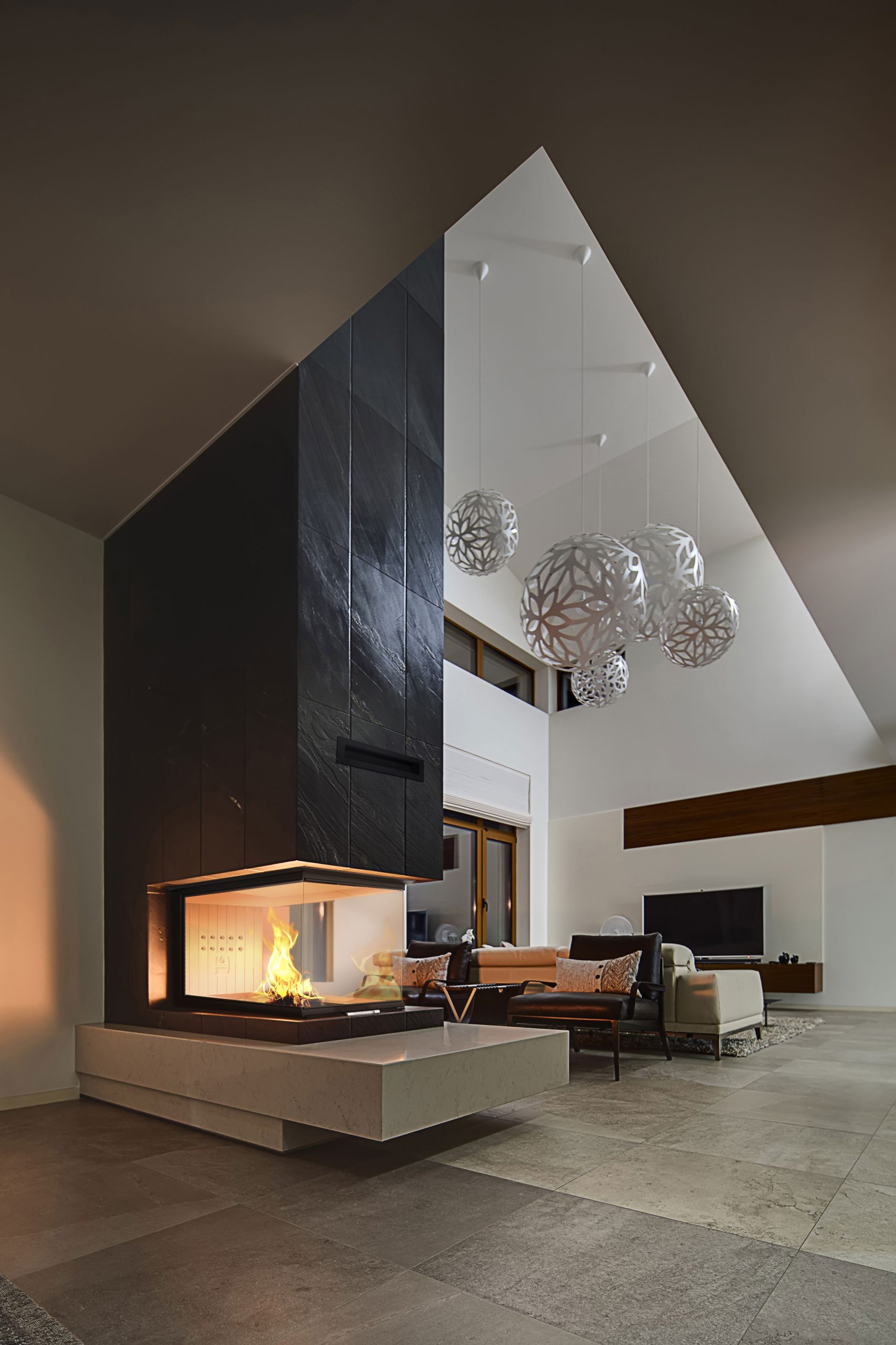 HITZE Trinity U tresidig insatskamin integrerad i exklusiv arkitektur med högt i tak och modern inredning.