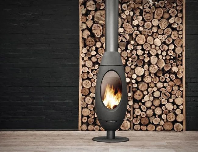 Invicta Ode gjutjärnskamin framför vedvägg, fransk braskamin i gjutjärn med oval design
